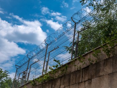 Mavi gökyüzüne karşı dikenli telden yapılmış hapishane çiti. Özgürlük arzusu.