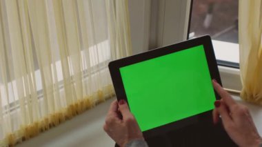 Tablet with green screen and chroma key for copy space. The woman touches the screen to control the screen. Modern devices and work on them.