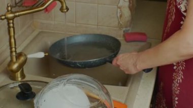 Womans hand washing a dirty frying pan with a sponge with foam. Washing dirty greasy dishes in the kitchen close-up. Washing dishes and cleaning in the kitchen.