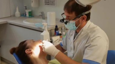 The patient is in the dental chair with her mouth open while the dentist treats her teeth. The concept of dental care.