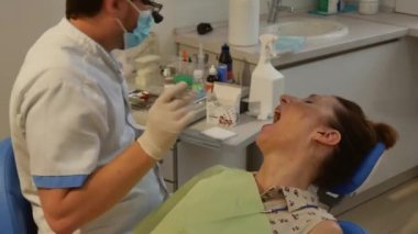 The patient is in the dental chair with her mouth open while the dentist treats her teeth. The concept of dental care.
