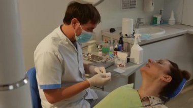 The patient is in the dental chair, and the dentist treats her teeth. Health care concept.