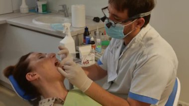 The patient is in the dental chair with her mouth open while the dentist treats her teeth. The concept of dental care.