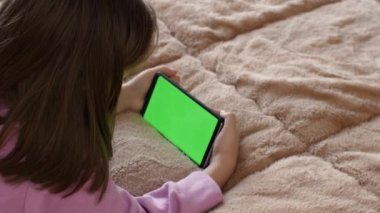 Küçük bir kızın elinde, yeşil ekran krom anahtarlı akıllı telefonunu kullanarak bir cep telefonunun yakın plan görüntüsü..