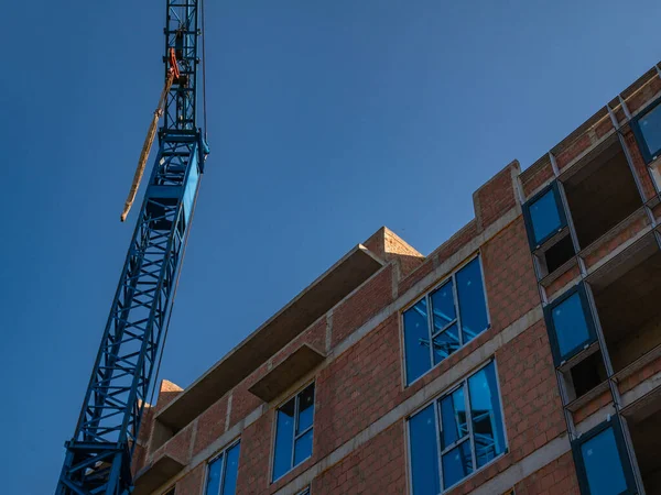 Construction crane with remote control against the background of the building under construction and the blue sky. Modern construction of high-rise buildings.