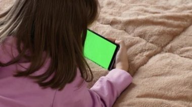 Küçük bir kızın elinde, yeşil ekran krom anahtarlı akıllı telefonunu kullanarak bir cep telefonunun yakın plan görüntüsü..