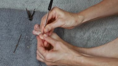 With a metal scraper, remove the cuticle of the toes. The concept of female pedicure and foot care. Copy space, close-up. UHD 4K.