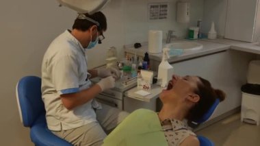 The patient is in the dental chair, and the dentist treats her teeth. Health care concept.