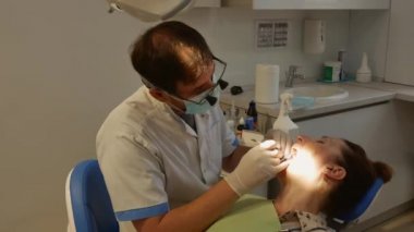 The patient is in the dental chair with her mouth open while the dentist treats her teeth. The concept of dental care.
