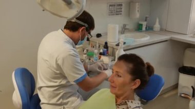 The patient is in the dental chair with her mouth open while the dentist treats her teeth. Health care