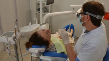 The patient is in the dental chair, and the dentist treats her teeth. Health care concept.