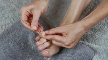 With a metal scraper, remove the cuticle of the toes. The concept of female pedicure and foot care. Copy space, close-up. UHD 4K.