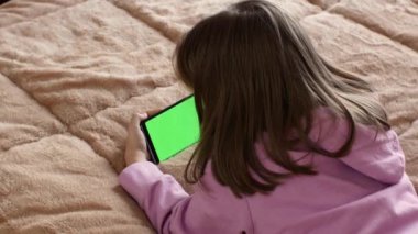 7-8 yaşlarında küçük bir kız, önceden ayarlanmış yeşil ekranlı akıllı telefon kullanıyor. Birkaç çeşit jest - sola-sağa kaydırma, dokunma. Ekran düzeni için ideal. Krom anahtar. yeşil ekran.