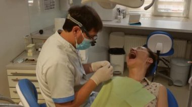The patient is in the dental chair with her mouth open while the dentist treats her teeth. The concept of dental care.
