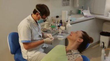 The patient is in the dental chair with her mouth open while the dentist treats her teeth. Health care