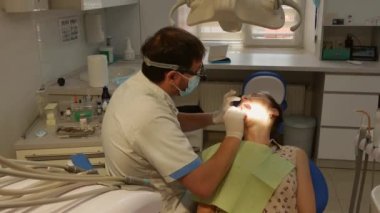 The patient is in the dental chair, and the dentist treats her teeth. Health care concept.