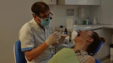 The patient is in the dental chair with her mouth open while the dentist treats her teeth. Health care