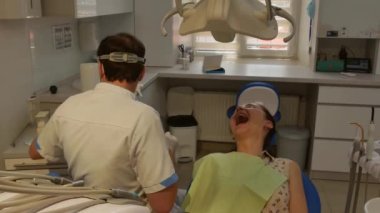 The patient is in the dental chair with her mouth open while the dentist treats her teeth. Health care