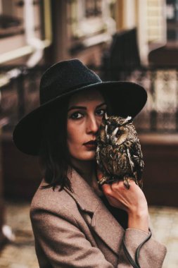 very beautiful girl in a hat with an owl. High quality photo