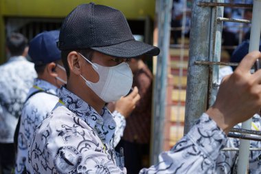 Siyah şapkalı Endonezyalı devlet memurları bir şey görmeye odaklanmışlar.