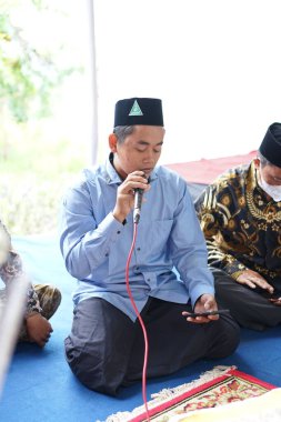 Dua etmek için mikrofon tutan bir adam