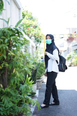 A girl prepares to take part in the cpns selection for the republic of indonesia, with the procedure of wearing a white shirt, black pants  mask