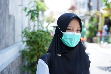 A girl prepares to take part in the cpns selection for the republic of indonesia, with the procedure of wearing a white shirt, black pants  mask