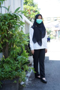 A girl prepares to take part in the cpns selection for the republic of indonesia, with the procedure of wearing a white shirt, black pants  mask