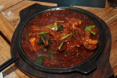 Fried ribs covered in sauce on a hot plate