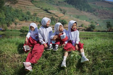 Indonesian elementary school students sitting by the lake