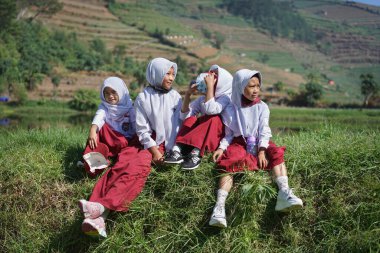 Indonesian elementary school students sitting by the lake