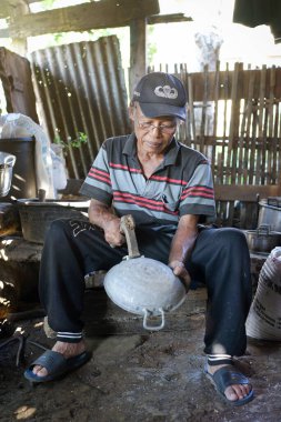 An old blacksmith is making a pot