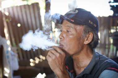 yaşlı bir adam sigara içiyor