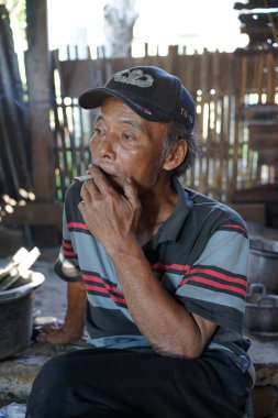 yaşlı bir adam sigara içiyor