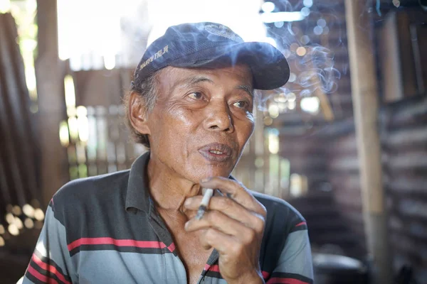 yaşlı bir adam sigara içiyor