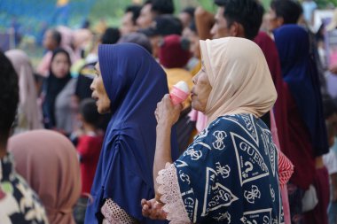 Granny eating ice cream in the crowd