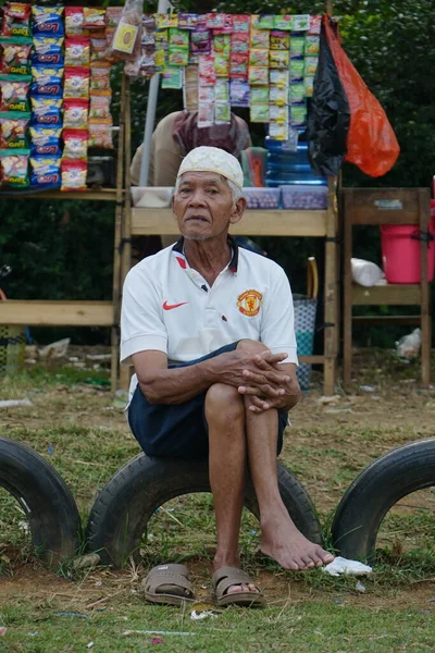 Old man sitting on old tires