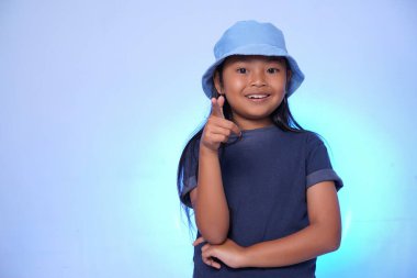 Mavi arka planda kameraya poz veren neşeli bir çocuk.