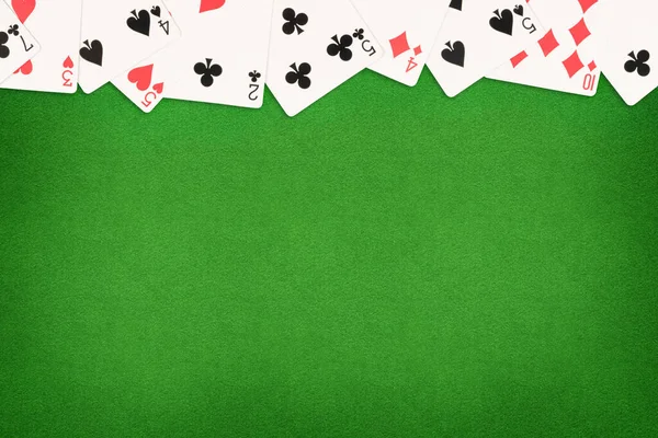 Cards on green felt casino table background. Template with copy space in center