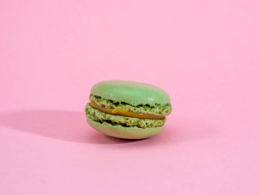 Pembe arka planda duran şam fıstıklı makaron.