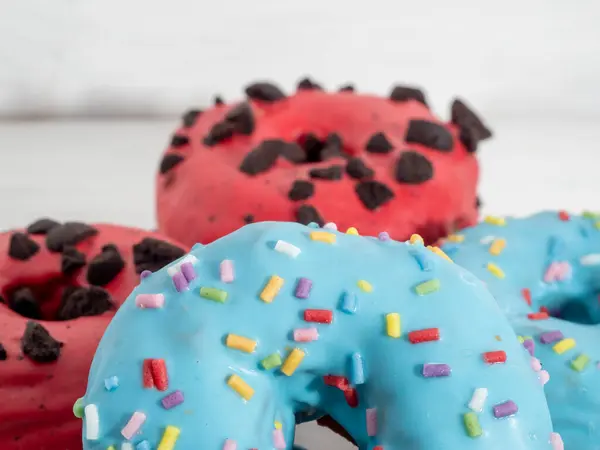 Красные и голубые пончики на белом деревянном фоне. — стоковое фото