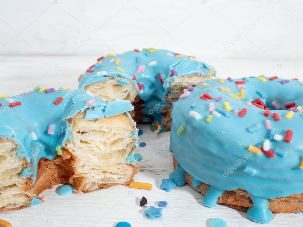 Blue cronuts on a white wooden background.