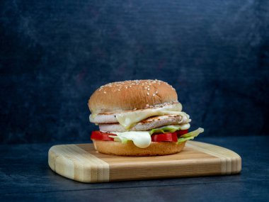 Salatalı sığır burger, siyah ahşap bir masanın üzerinde peynir..