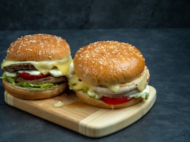 Salatalı sığır burger, siyah ahşap bir masanın üzerinde peynir..