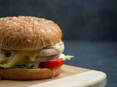 Salatalı sığır burger, siyah ahşap bir masanın üzerinde peynir..