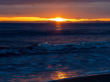 Gün batımında resimli deniz manzarası, denizdeki güneş ışığının altın yansıması..