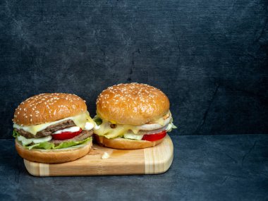 Salatalı sığır burger, siyah ahşap bir masanın üzerinde peynir..