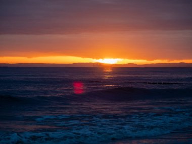 Gün batımında resimli deniz manzarası, denizdeki güneş ışığının altın yansıması..
