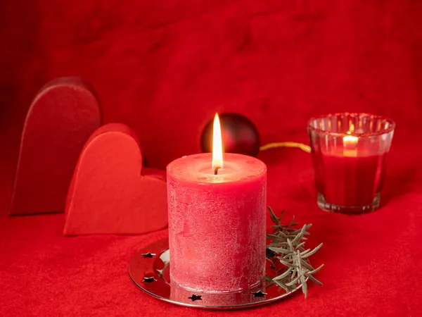 Czerwona świeca świąteczna i dekoracje świąteczne na czerwonym tle. — Zdjęcie stockowe
