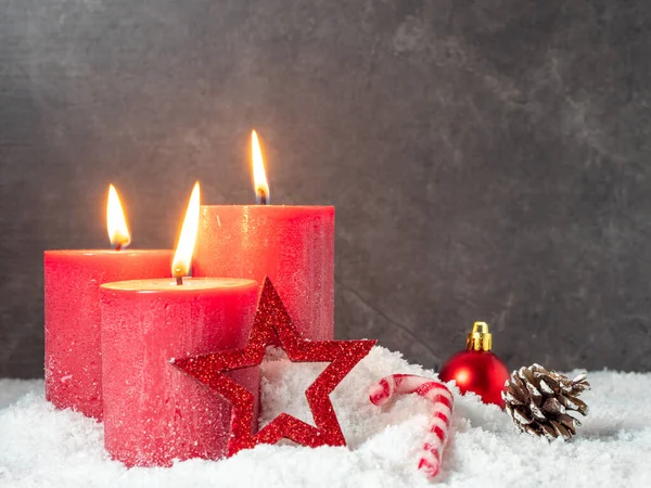 Красная рождественская свеча и рождественские украшения на сером фоне. — стоковое фото